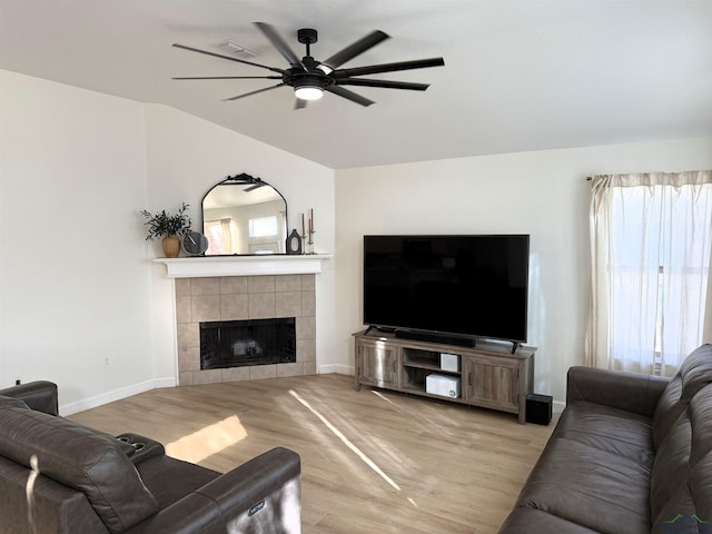 living room featuring ceiling fan, light wood-type flooring, and a tile fireplace