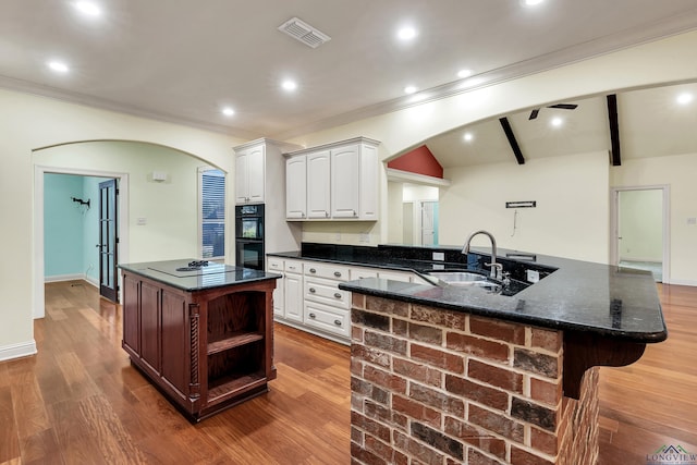 kitchen with sink, lofted ceiling with beams, double oven, a breakfast bar area, and white cabinets