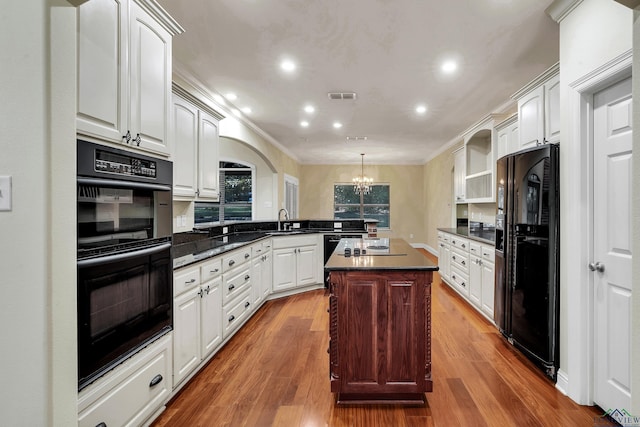 kitchen with kitchen peninsula, black appliances, a chandelier, a center island, and white cabinetry