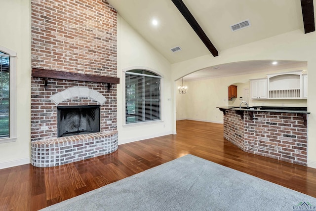 unfurnished living room featuring a fireplace, beam ceiling, hardwood / wood-style flooring, and high vaulted ceiling