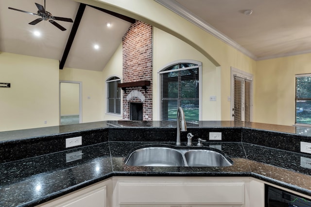 kitchen with dark stone counters, ceiling fan, sink, a fireplace, and white cabinetry