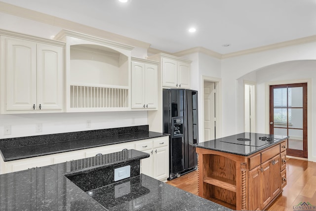 kitchen featuring dark stone countertops, open shelves, arched walkways, light wood-type flooring, and black appliances