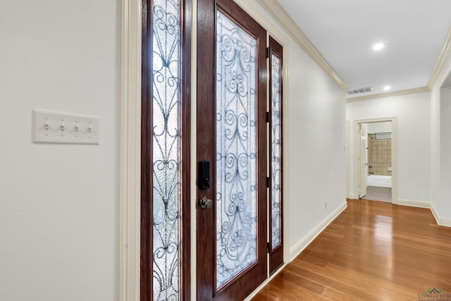 entryway featuring visible vents, baseboards, ornamental molding, light wood finished floors, and recessed lighting