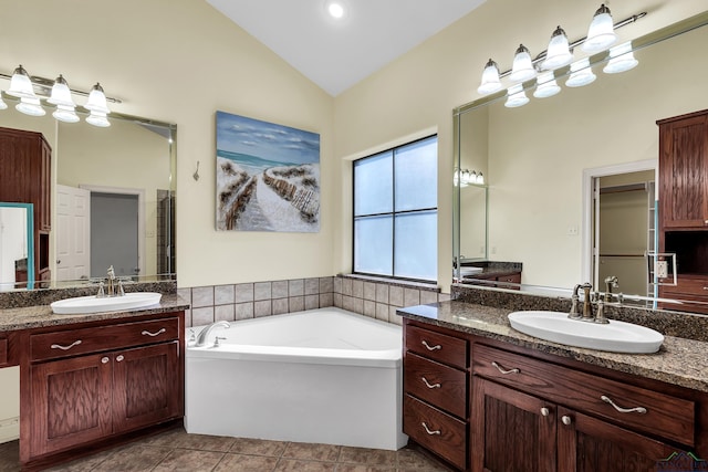 bathroom with a bathing tub, tile patterned flooring, vanity, and vaulted ceiling