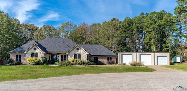 french provincial home with an outbuilding, a garage, a shingled roof, stone siding, and a front yard