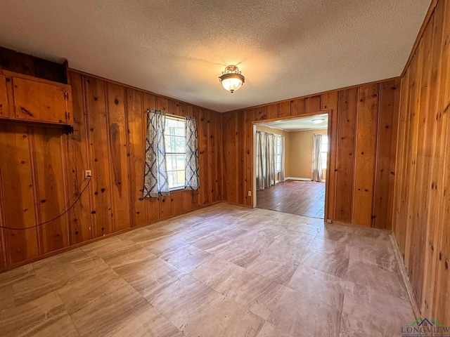 unfurnished room featuring a textured ceiling and wooden walls