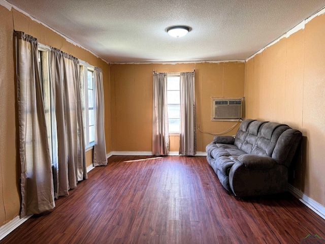 unfurnished room with dark wood-type flooring, a textured ceiling, and an AC wall unit