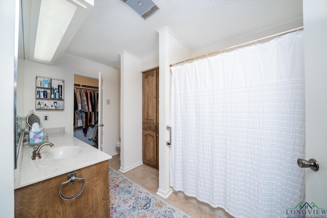 bathroom featuring a textured ceiling, tile patterned flooring, vanity, toilet, and ornamental molding