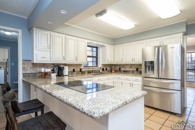 kitchen with stainless steel refrigerator with ice dispenser, white cabinetry, decorative backsplash, and kitchen peninsula