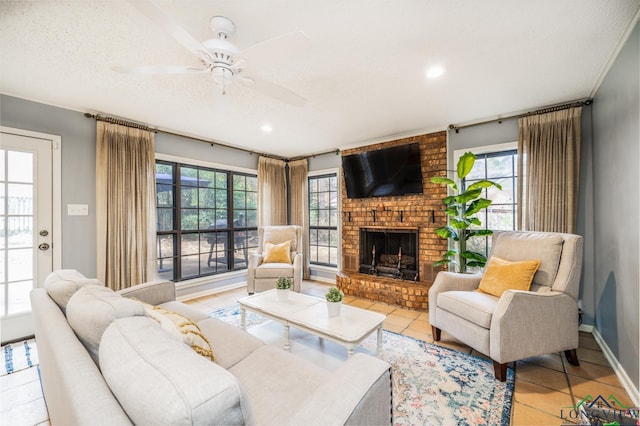 living room with ceiling fan, a textured ceiling, a brick fireplace, and light tile patterned flooring