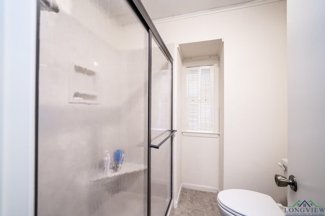 bathroom featuring toilet, crown molding, and a shower with door