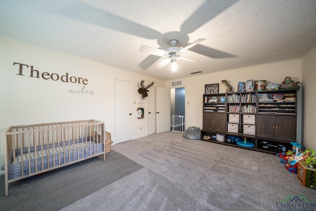 carpeted bedroom with a textured ceiling, ceiling fan, and a nursery area