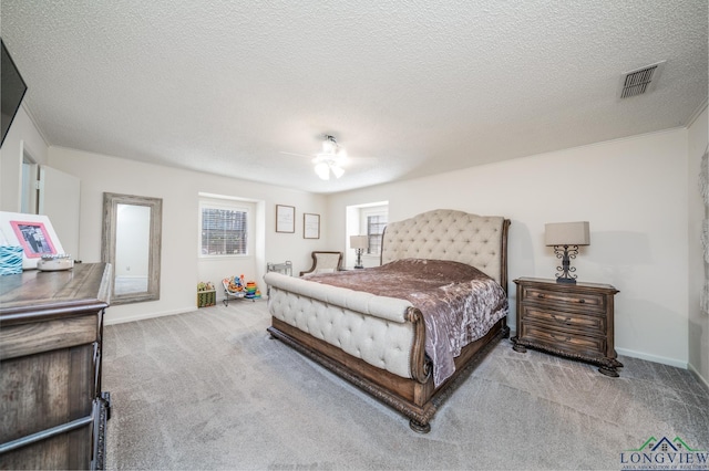 bedroom featuring a textured ceiling, ceiling fan, and light colored carpet