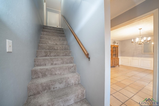 stairs with a notable chandelier, tile patterned floors, and a textured ceiling