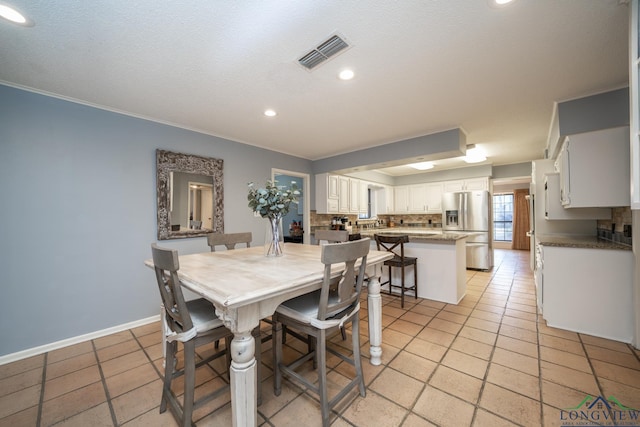 dining area featuring light tile patterned floors and ornamental molding