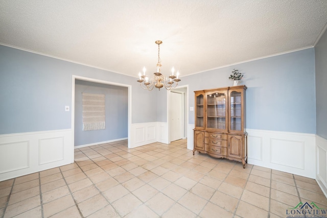 unfurnished dining area featuring light tile patterned floors, crown molding, and a chandelier