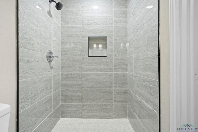 bathroom featuring toilet and tiled shower