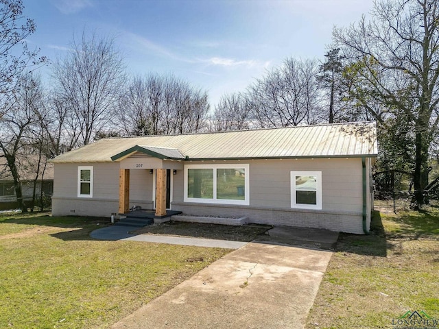 view of front of property featuring metal roof, brick siding, and a front lawn