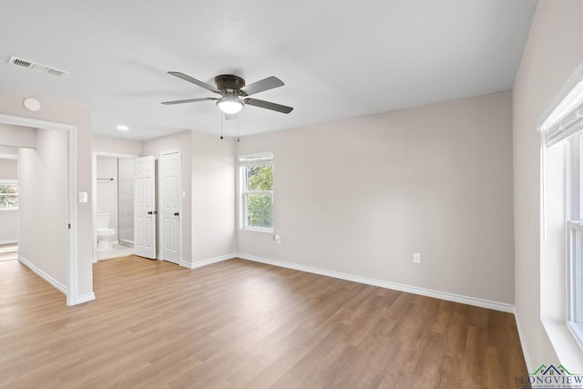 unfurnished room with a ceiling fan, light wood-type flooring, visible vents, and baseboards