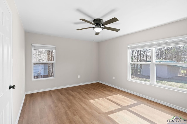 empty room featuring light wood-type flooring, baseboards, and a ceiling fan