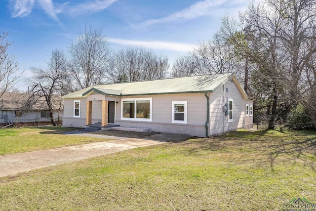 view of front of house featuring metal roof, brick siding, and a front yard