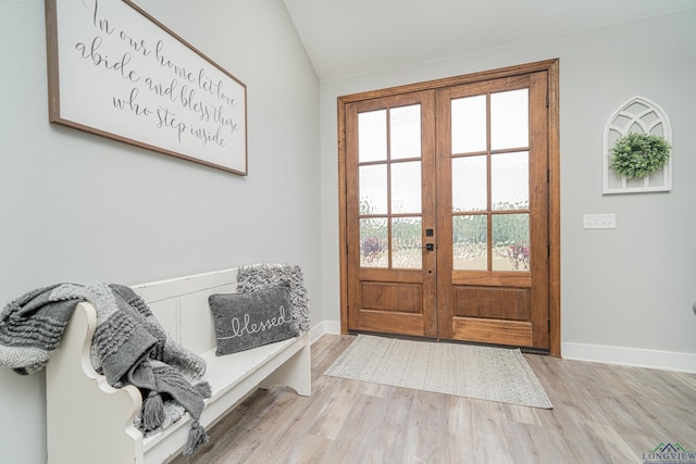 doorway featuring light hardwood / wood-style floors, vaulted ceiling, and french doors