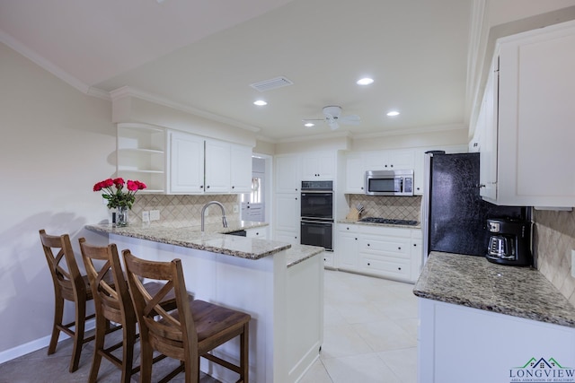 kitchen featuring crown molding, light stone countertops, a peninsula, black appliances, and backsplash