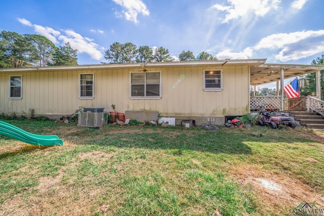 rear view of property with a playground and a yard