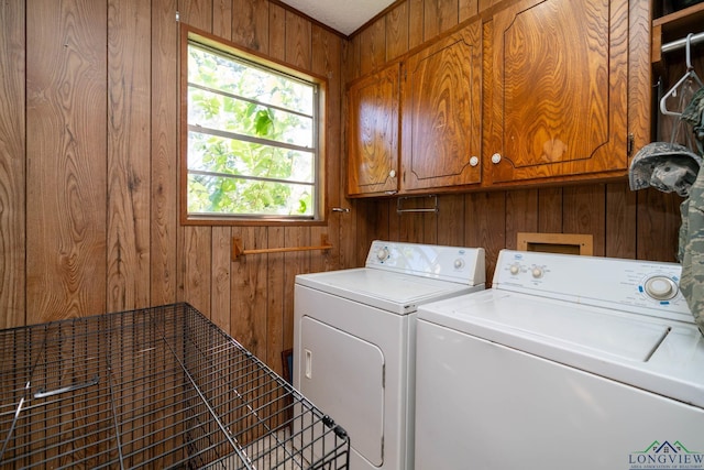 laundry area with cabinets, wooden walls, and washing machine and clothes dryer