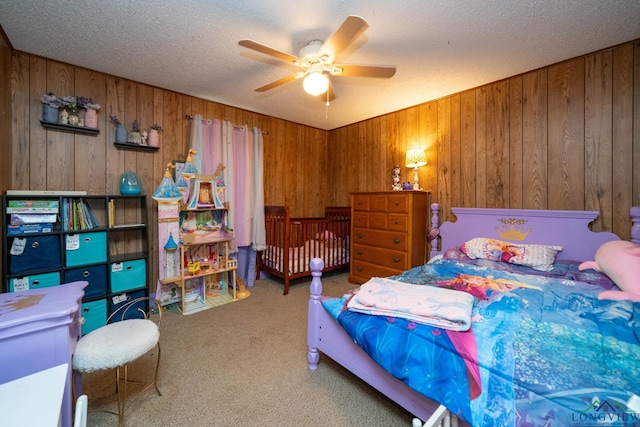 carpeted bedroom with a textured ceiling, ceiling fan, and wood walls