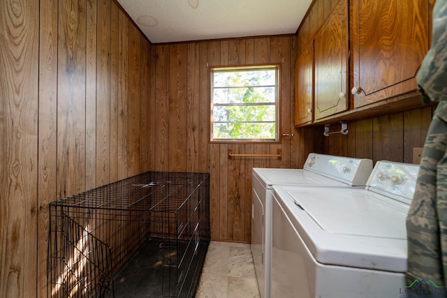 laundry room featuring cabinets, wood walls, and washing machine and clothes dryer