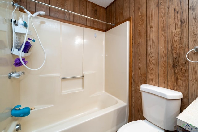 bathroom featuring wood walls, toilet, and washtub / shower combination