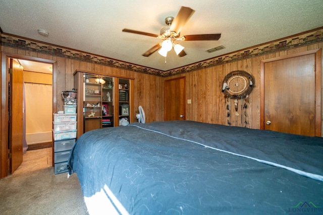 bedroom featuring light carpet, a textured ceiling, ceiling fan, and wood walls