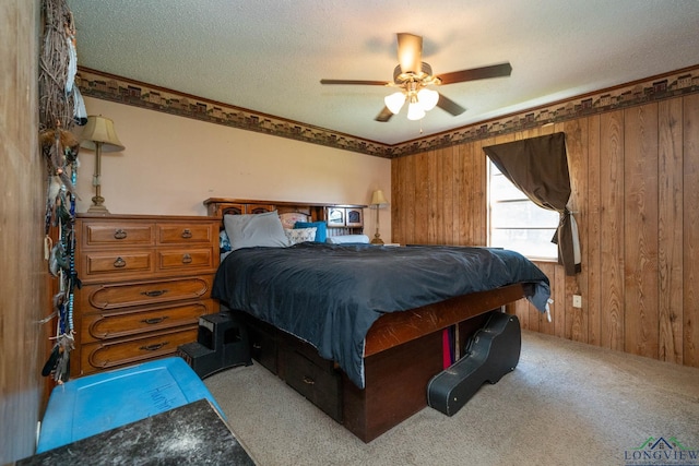 bedroom featuring a textured ceiling, ceiling fan, light colored carpet, and wood walls