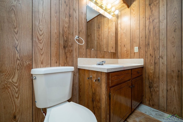 bathroom with vanity, toilet, and wood walls