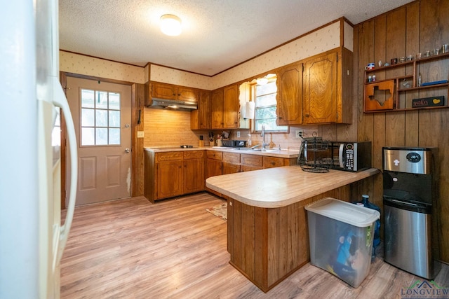 kitchen featuring kitchen peninsula, white refrigerator, light hardwood / wood-style flooring, and a wealth of natural light