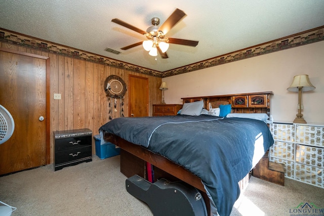 carpeted bedroom featuring ceiling fan, a textured ceiling, and wooden walls