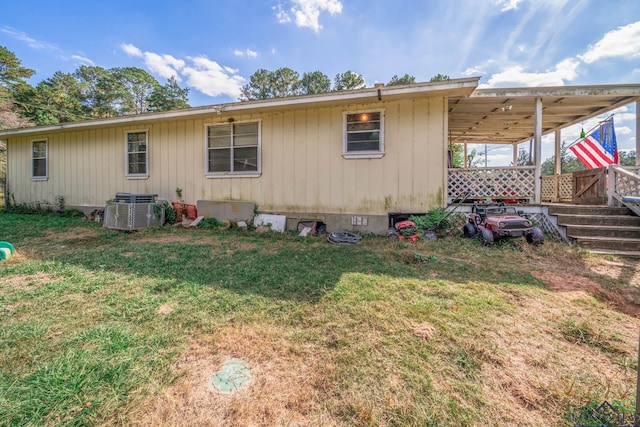 rear view of house featuring cooling unit and a lawn