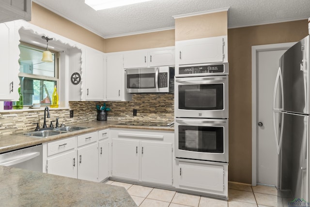 kitchen with white cabinets, sink, decorative backsplash, light tile patterned floors, and appliances with stainless steel finishes