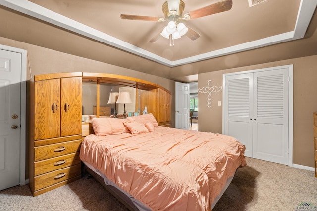 carpeted bedroom featuring a raised ceiling and ceiling fan