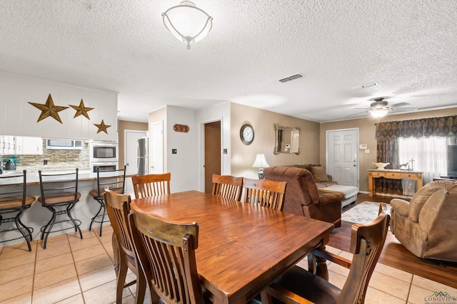 dining room featuring ceiling fan, light tile patterned floors, and a textured ceiling