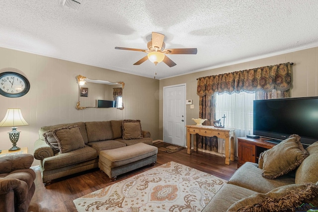 living room with a textured ceiling, dark hardwood / wood-style flooring, ceiling fan, and ornamental molding