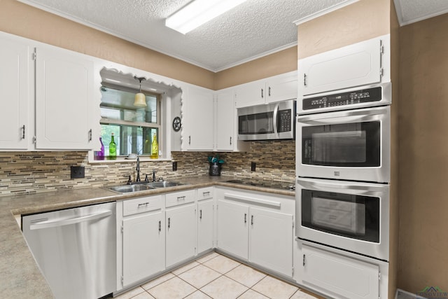 kitchen with backsplash, stainless steel appliances, sink, white cabinetry, and light tile patterned flooring