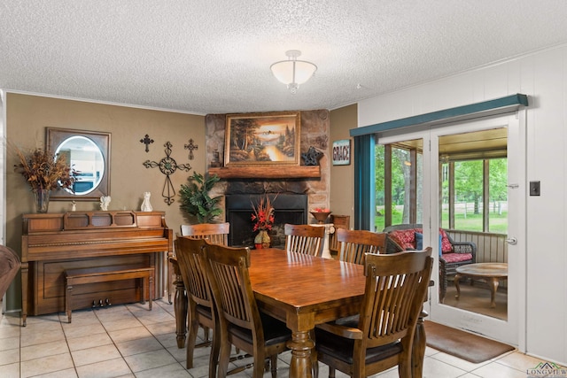 dining room featuring a stone fireplace, light tile patterned floors, and a textured ceiling