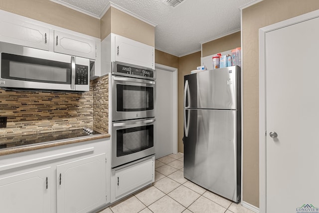 kitchen featuring white cabinets, a textured ceiling, appliances with stainless steel finishes, tasteful backsplash, and light tile patterned flooring