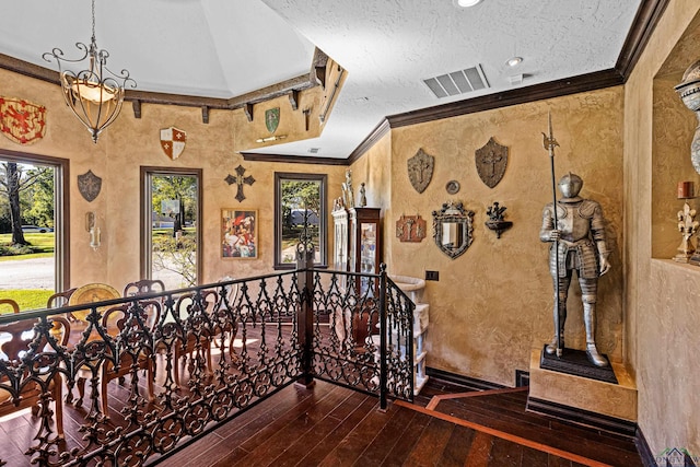 staircase with crown molding, vaulted ceiling, a textured ceiling, a notable chandelier, and wood-type flooring