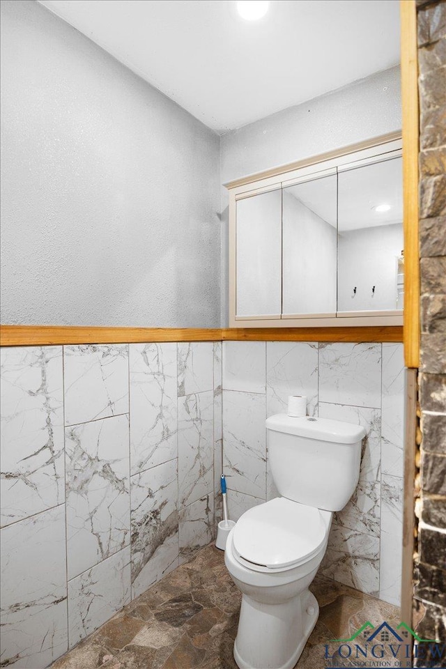 501 S Harrison St, Longview, TX 75601 - half bathroom featuring toilet, tile walls, and wainscoting