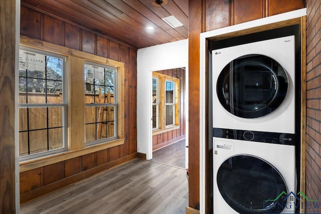 501 S Harrison St, Longview, TX 75601 - washroom featuring stacked washer / dryer, wooden ceiling, wood finished floors, wood walls, and baseboards