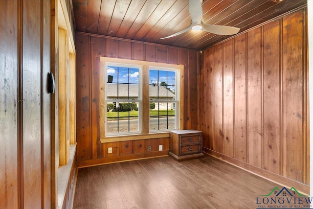 501 S Harrison St, Longview, TX 75601 - spare room featuring wood finished floors, wooden ceiling, baseboards, wood walls, and a ceiling fan