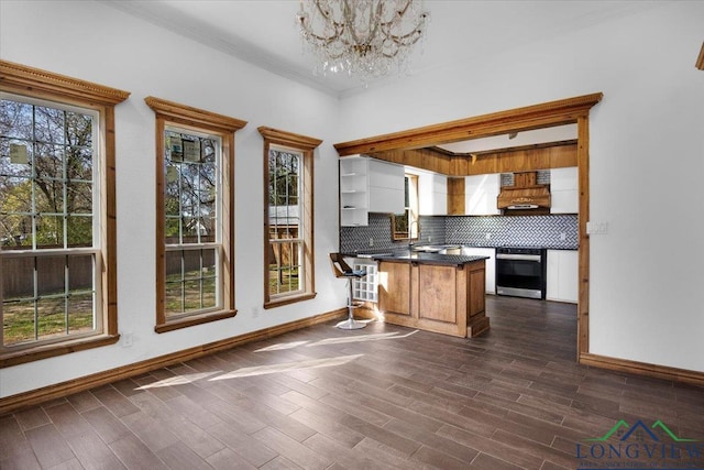 501 S Harrison St, Longview, TX 75601 - kitchen featuring custom exhaust hood, dark countertops, a chandelier, a peninsula, and decorative backsplash